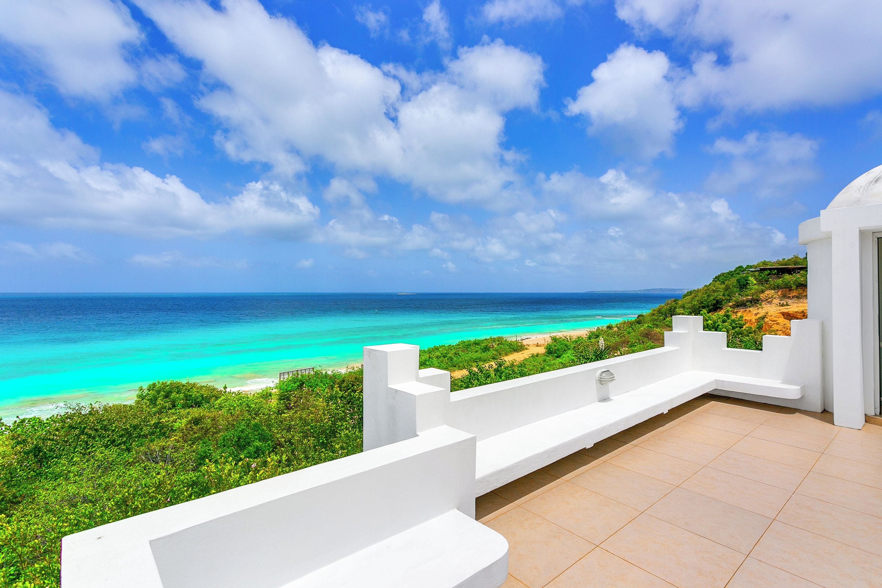 A white building with a view of a turquoise sea and a clear sky.