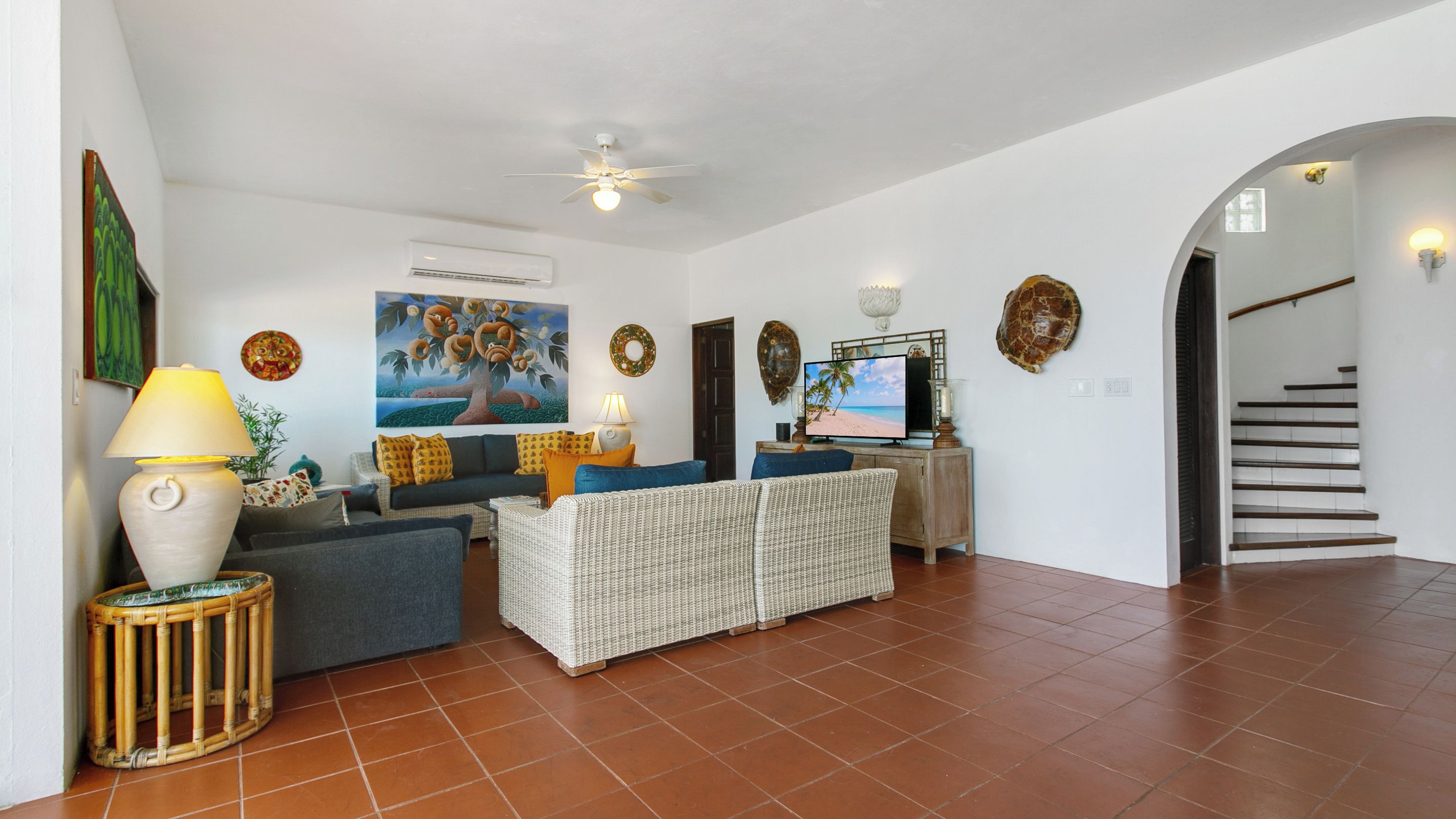 A spacious living area with a sofa, armchairs, a television, and a decorative wall.