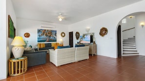 Un amplio salón con sofá, sillones, televisor y un detalle decorativo en la pared.
