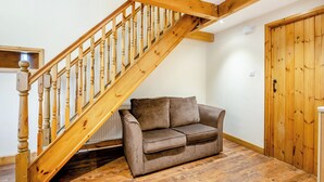 A wooden staircase with a brown leather sofa in a room with wooden flooring and a wooden door. - The Granary - UK44520 (Holton-Le-Clay, near Cleethorpes)