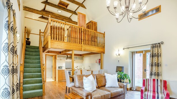 A spacious living area with a high ceiling, wooden staircase, and a cozy seating arrangement. - The Granary - UK44520 (Holton-Le-Clay, near Cleethorpes)