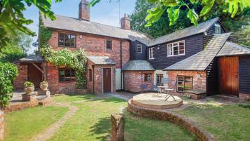 A brick house with a garden, a wooden deck, and a brick wall.