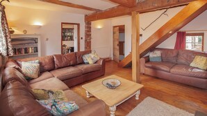 Una sala de estar acogedora con sofás de cuero marrón, una mesa de centro de madera y una escalera.