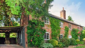 A brick house with ivy and flowering plants.