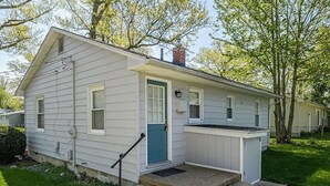 Ein eingeschossiges Haus mit Veranda, einer blauen Tür und einem kleinen Vorgarten.