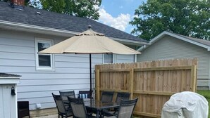 Eine Terrasse mit Tisch und Stühlen, einem Sonnenschirm und einem Holzzaun.