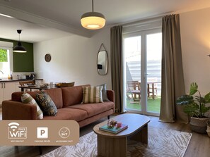 A modern living room with a sofa, coffee table, and a dining area. - LE Cinquieme (Bressuire)