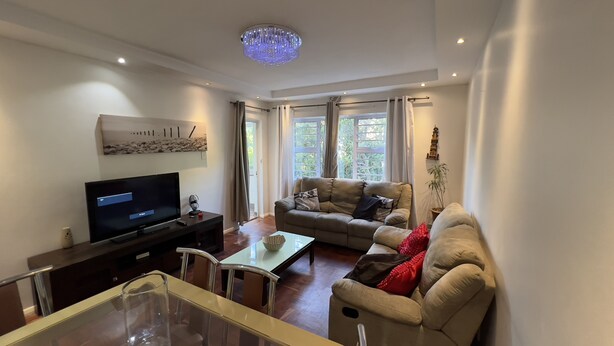 A living room with a television, sofa, and a glass coffee table.