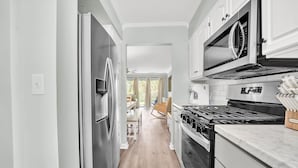 Eine moderne Küche mit Edelstahlgeräten, weißen Schränken und Holzboden.