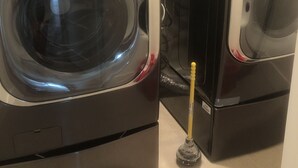 Two front-loading washing machines in a laundry room with a visible control panel and a yellow plunger. - Joy's Melissa House (Melissa)
