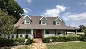 A two-story house with a front porch, a red door, and a stone pathway leading to the entrance. - Joy's Melissa House (Melissa)