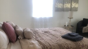 A bedroom with a bed, pillows, a lamp, and a window. - Joy's Melissa House (Melissa)