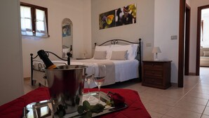 A bedroom with a bed, a bedside table, a nightstand, a window, and a painting on the wall.
