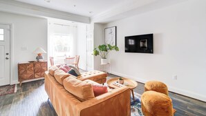 Uma sala de estar moderna com sofá, pufes, mesa de centro e uma planta em vaso.