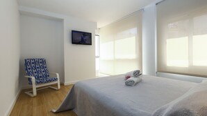 A hotel room with a bed, a chair, a television, and a window. - TOUS 2 Apartment - Only Families (Salou)