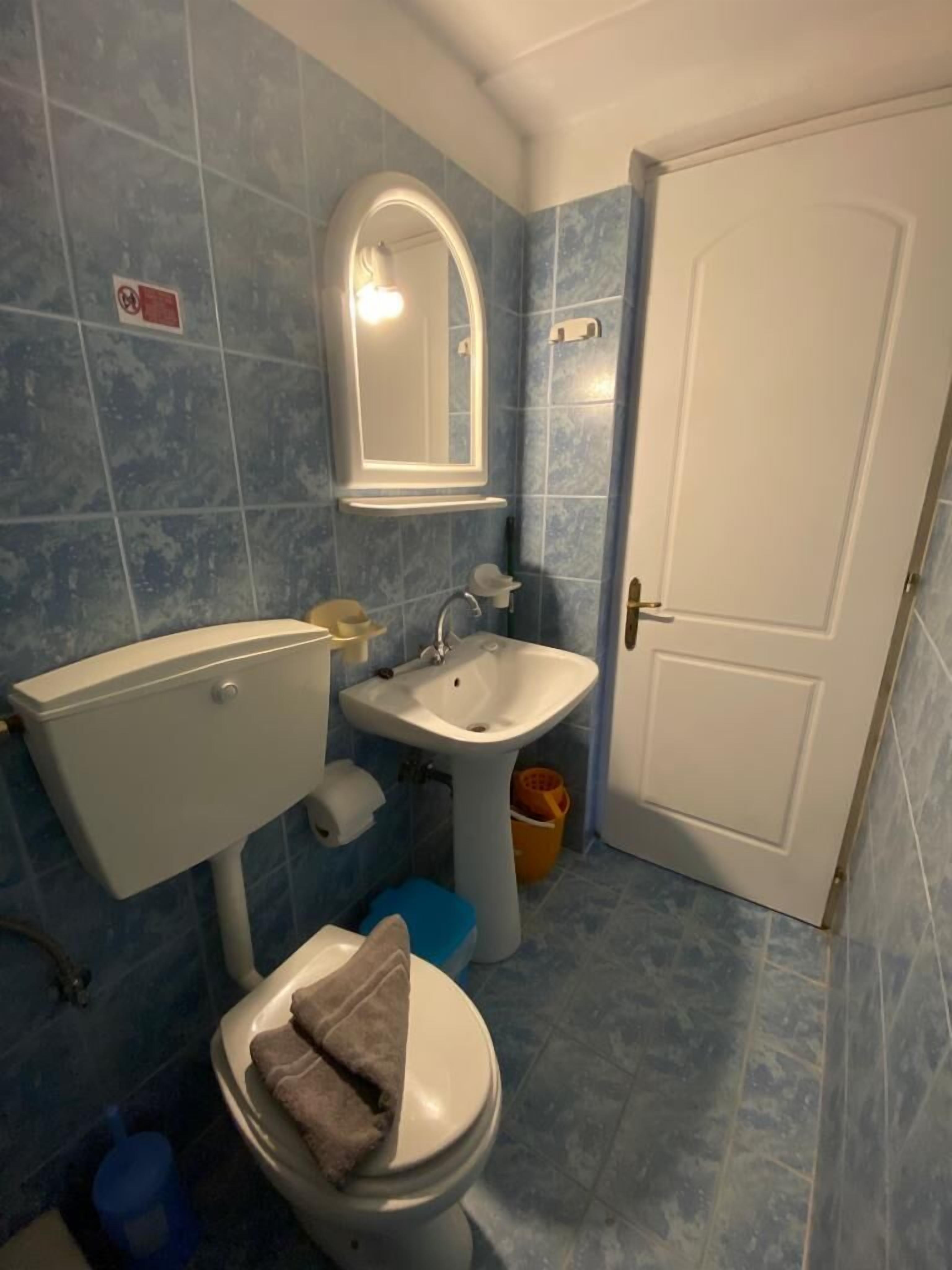 A bathroom with a toilet, sink, and mirror.