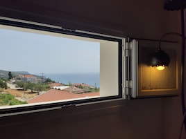 Una habitación con un ventanal grande que ofrece vistas a un pueblo costero y al mar.