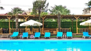 A pool area with blue lounge chairs and white umbrellas. - Hotel Genatsvale Batumi (Batumi)