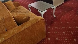 A hotel room with a bed, a sofa, a small table, and a window with curtains. - Hotel Genatsvale Batumi (Batumi)