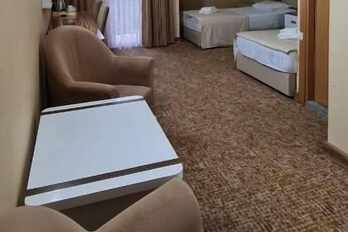 A hotel room with a large bed, a smaller bed, a sofa, a table, and a chair.
