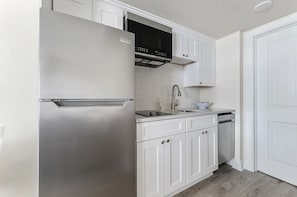 Una cocina moderna con armarios blancos, electrodomésticos de acero inoxidable y un microondas integrado.