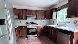 A modern kitchen with wooden cabinets, stainless steel appliances, and a granite countertop.