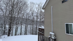 A residential building with a beige exterior, a wooden deck, and a snow-covered yard.