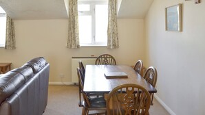 A dining room with a wooden table and chairs, a leather bench, and a radiator. - Pirates Cove - UK44493 (Hope Cove, near Kingsbridge)
