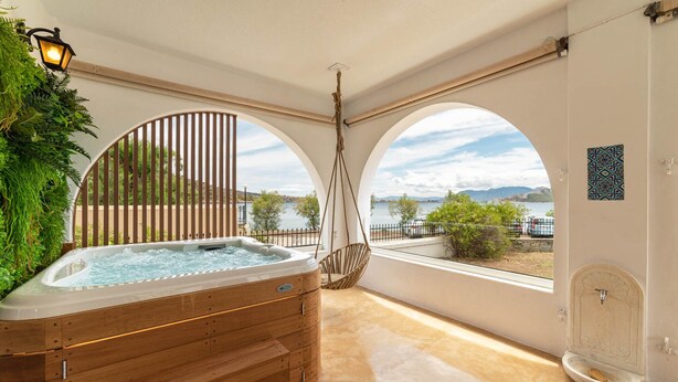 Een wellnessruimte met een jacuzzi, een schommelstoel en uitzicht op zee.