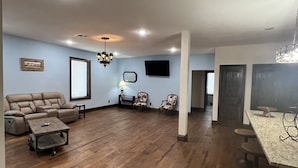 A spacious living room with a sectional sofa, a coffee table, and a dining area with a bar stool.