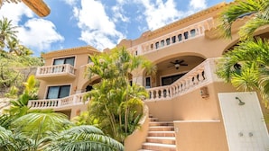 A multi-story building with a beige facade, balconies, and a staircase leading to an upper level.