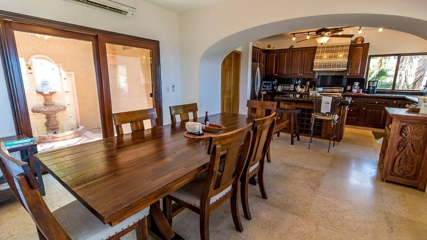 Ein geräumiger Essbereich mit Holztisch und -stühlen, eine Küche mit Holzausstattung und ein großes Fenster, das für natürliches Licht sorgt.