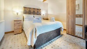 Un dormitorio con cama, armario de madera y mesita de noche.