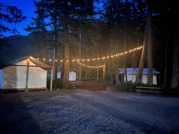 Un camping con tiendas de campaña y luces colgantes.