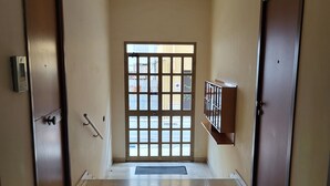A hallway with two doors, a large window, and a metal railing.