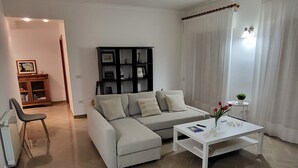 A modern living room with a sectional sofa, a white coffee table, and a black shelving unit.