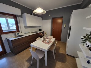 Enjoy meals in the central island kitchen with a sink and ample counter space, complemented by a dining area with a table and chairs.