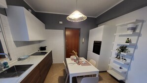 A modern kitchen with white cabinets, a wooden countertop, and a dining area with a white table and chairs.