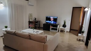 A modern living room with a beige sofa, a coffee table, a TV, and a small side table with a plant.