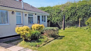 A single-story house with a tiled roof, a fenced garden, and a clear sky. - A great, three-bedroom bungalow, with front and back gardens. (Warbstow, near Crackington Haven)