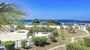 A resort with a pool, palm trees, and a view of the ocean. - Maison Caraïbes, sur la plage d`Orient Bay (Orient Bay)