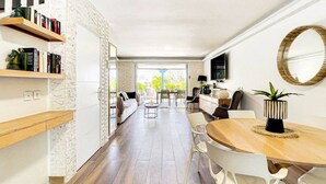 A modern kitchen with wooden flooring, white cabinets, and a dining area with a round table and chairs. - Maison Caraïbes, sur la plage d`Orient Bay (Orient Bay)