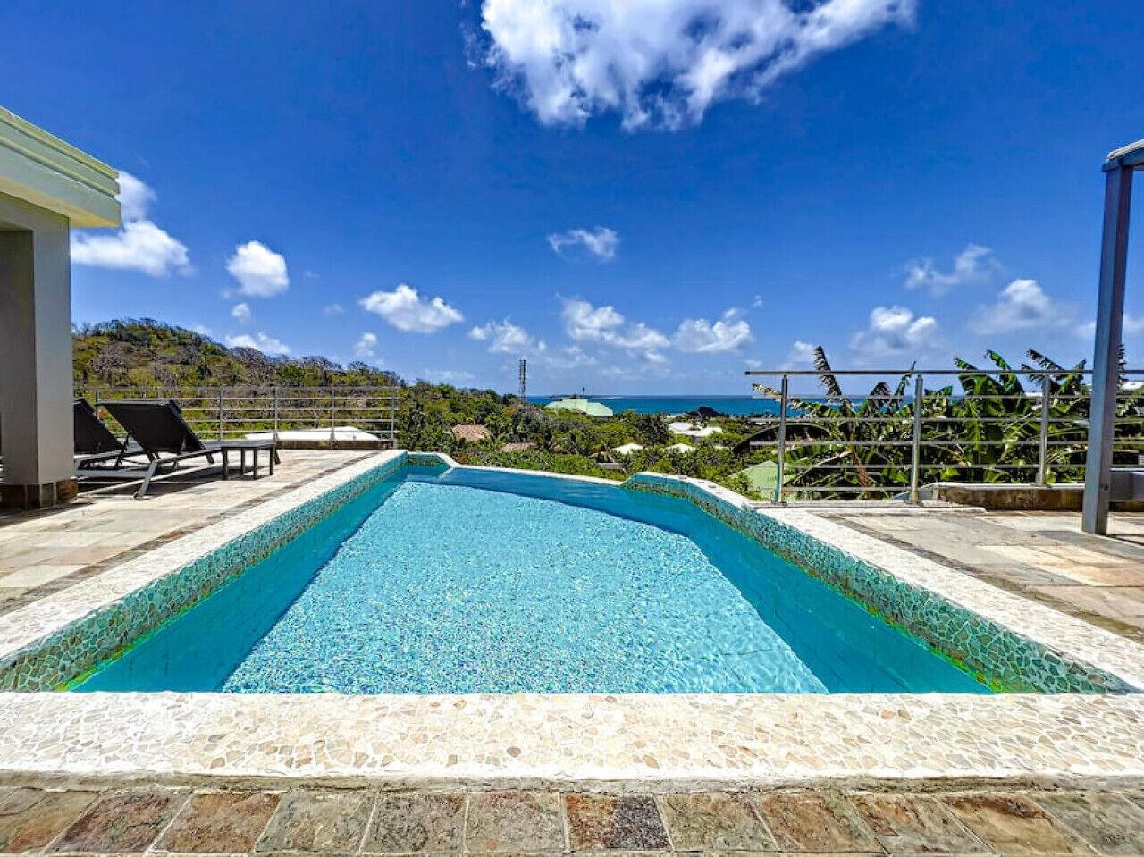 A rectangular pool with clear blue water, surrounded by a tiled deck.