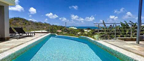 A rectangular pool with clear blue water, surrounded by a tiled deck.