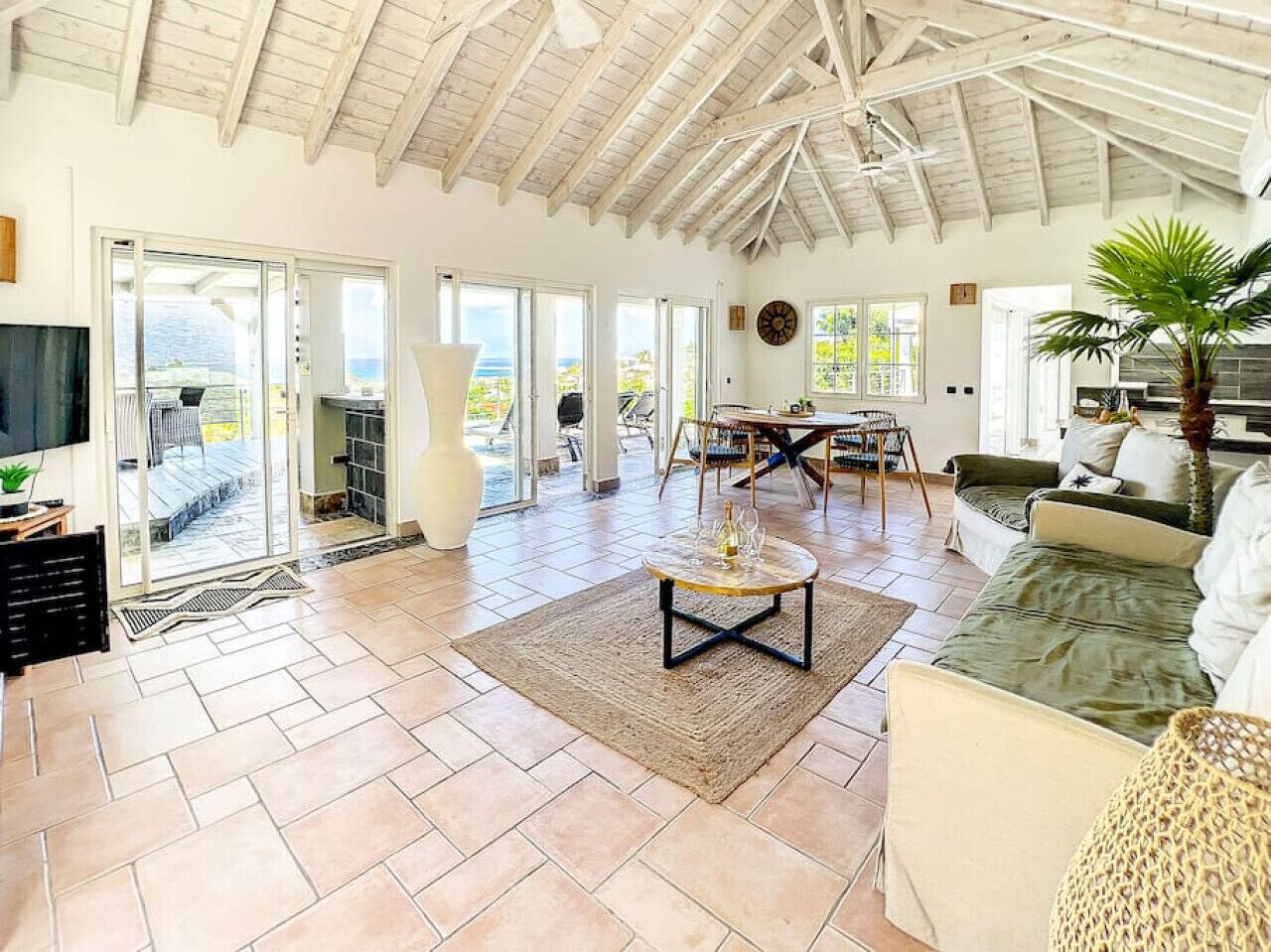A spacious living area with a high ceiling, a dining table, and a comfortable seating arrangement.