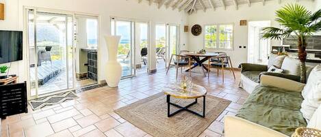 A spacious living area with a high ceiling, a dining table, and a comfortable seating arrangement.