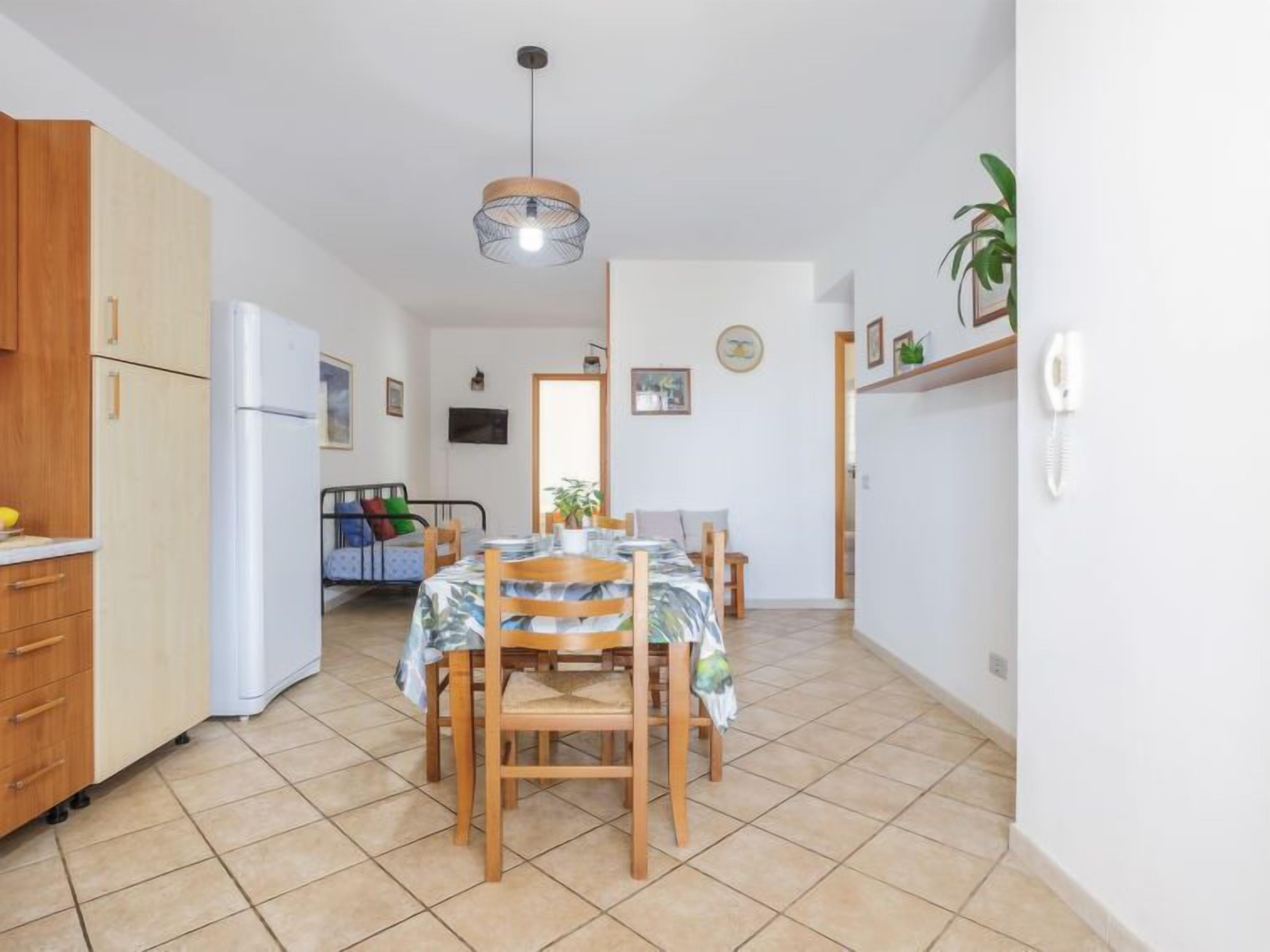 A compact kitchen with a dining area, a small seating area, and a single hanging light fixture.