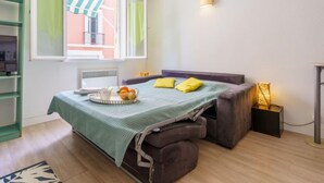 Un dormitorio pequeño con cama, mesita de noche y ventana con cortinas.