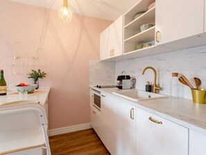 A modern kitchen with white cabinets, a marble countertop, and gold fixtures. - Le Clos Mathilde by Interhome (Cabourg)
