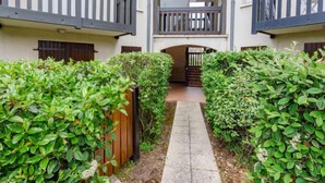 A courtyard with a central pathway flanked by lush greenery and wooden fences. - Le Clos Mathilde by Interhome (Cabourg)